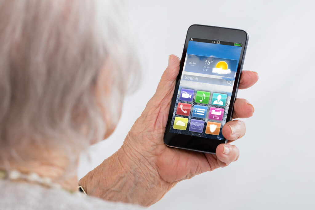 Close-up Of Senior Woman Holding Smartphone With Colorful Application Icons At Home