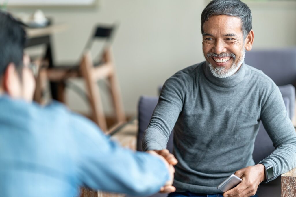 competitive as developer Confident mutaul asian man sitting, smiling and shaking hand with partnership after making profitable agreement. Smart man handshake, deal and greeting concept.