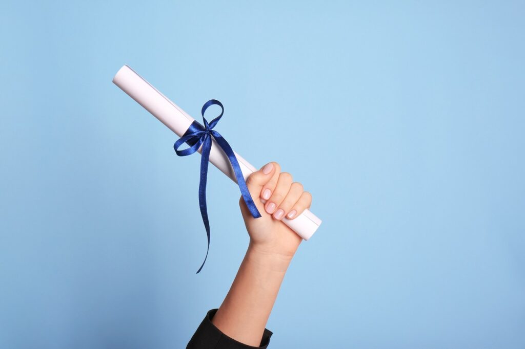 data science certificate Student holding rolled diploma with ribbon on light blue