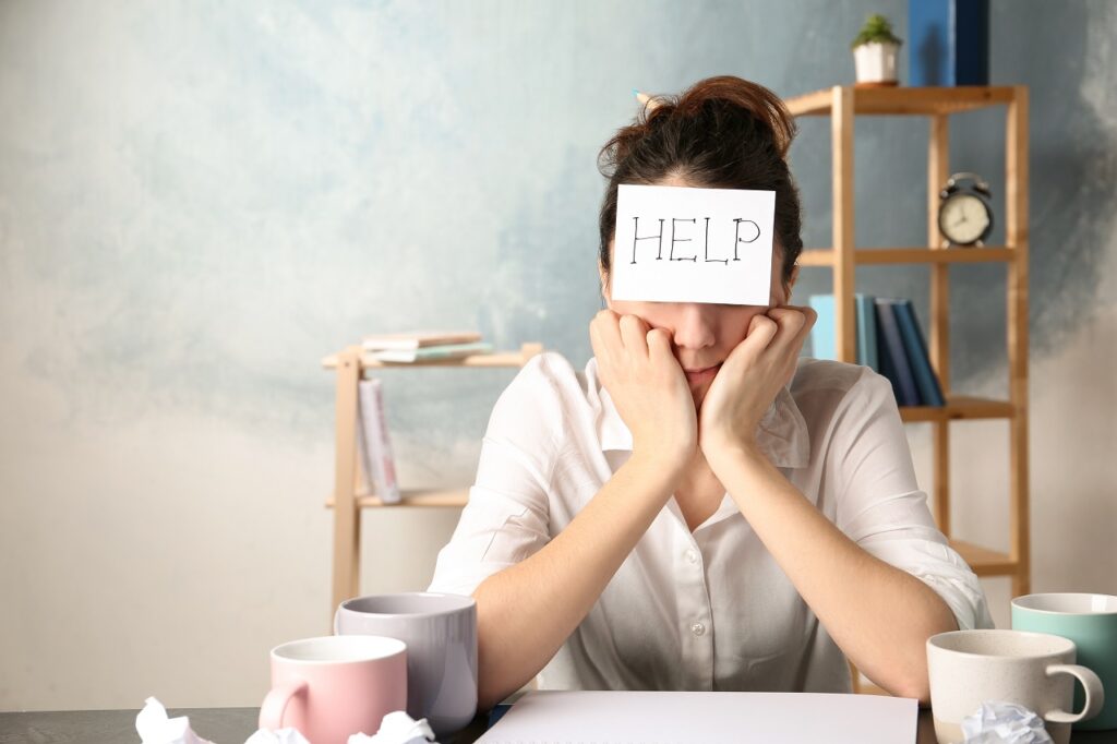web development Young woman with note HELP on forehead at workplace. Space for text
