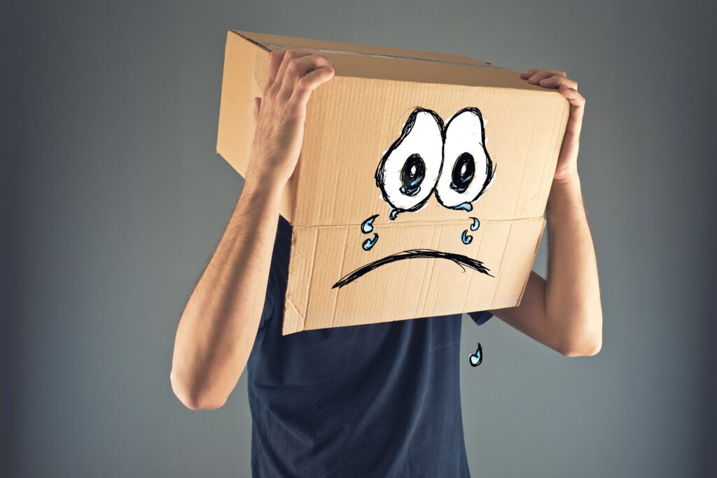 Man with cardboard box on his head and sad crying face expression. Concept of sadness and depression.