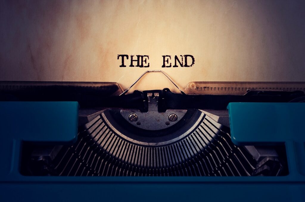 closeup of a blue retro typewriter and the text the end written with it in a yellowish foil
