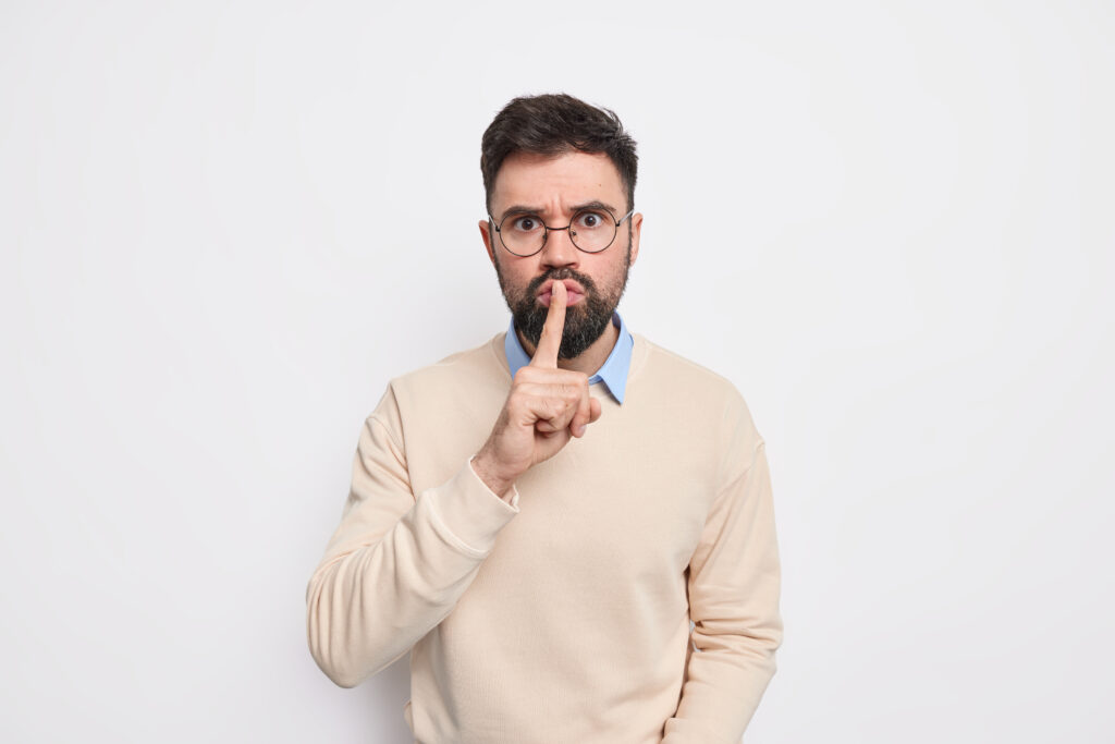 Bildungsgutschein courses Serious bearded man makes silence gesture prohibits to speak